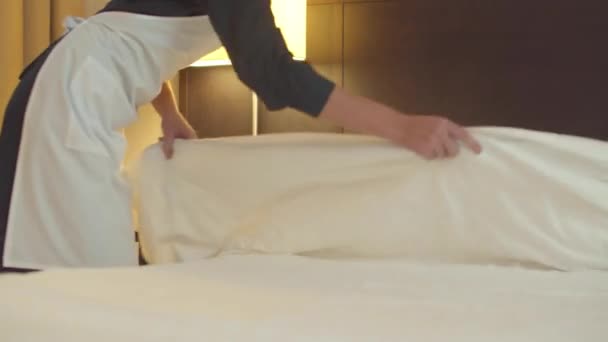 Housemaid κάνει ένα κρεβάτι και απλώστε μια κουβέρτα στο δωμάτιο του ξενοδοχείου  - Πλάνα, βίντεο