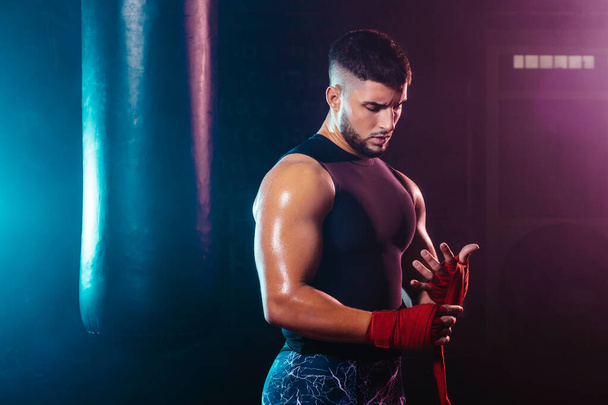 joven y musculoso hombre envolviendo sus manos con cinta de boxeo - lucha, deporte y boxeo temas
 - Foto, Imagen