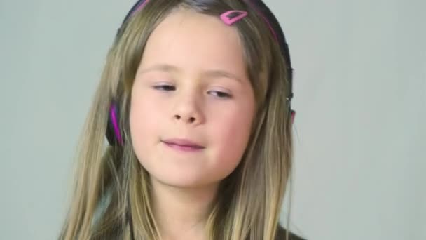 Bella sorridente ragazza cild ascoltare musica in grandi auricolari rosa
. - Filmati, video