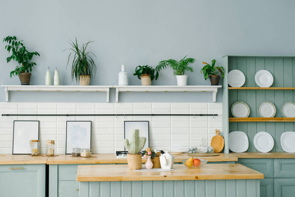 Skandinávský styl v interiéru kuchyně v bílých a mátových barvách. Bílé talíře, kytky - Fotografie, Obrázek