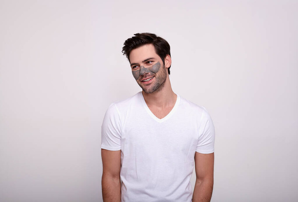 A satisfied young man poses on a white background in a face mask. - Fotografie, Obrázek