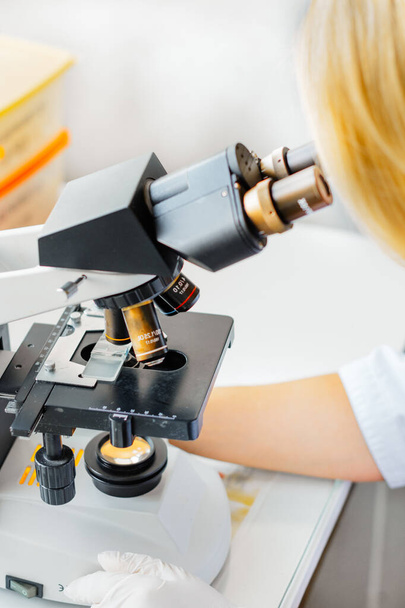 The lab technician looks into the microscope and records and analyzes the blood. - Photo, image