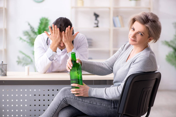 Female alcoholic visiting young male doctor - Photo, Image