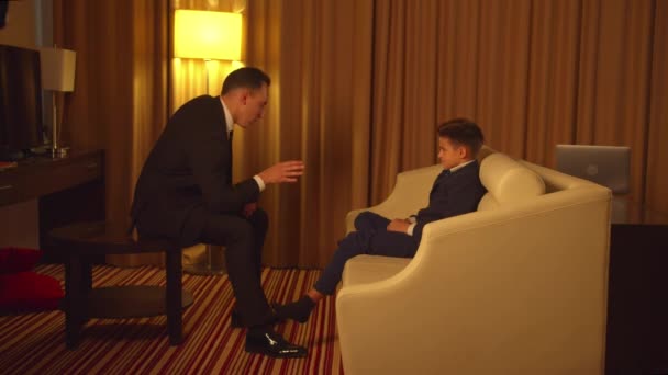 Biznes człowiek w garniturze siedzieć i rozmawiać z małym chłopcem w hotelu  - Materiał filmowy, wideo