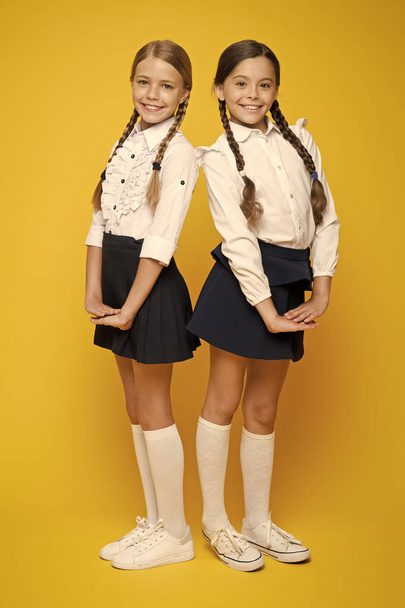 Best pupils award. Making everything right. Excellent pupils. Girls perfect uniform outfit on yellow background. According to school rules. Classmates tidy pupils. Educational program for gifted kids - Foto, Imagem