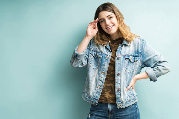 Fashionable good looking woman wearing denim jacket standing against blue background - Foto, immagini