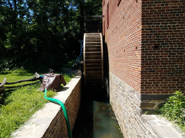 dřevěné vodní kolo a voda nebo potok v kanálu s kameny a cihlami - Fotografie, Obrázek