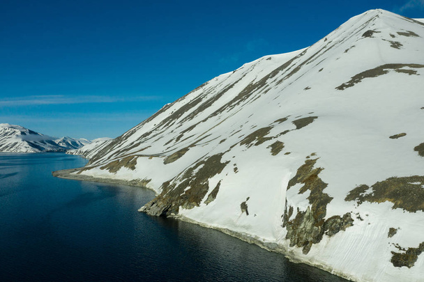 The mountainous sea coast covered with snow in a sunny weather. - Photo, Image