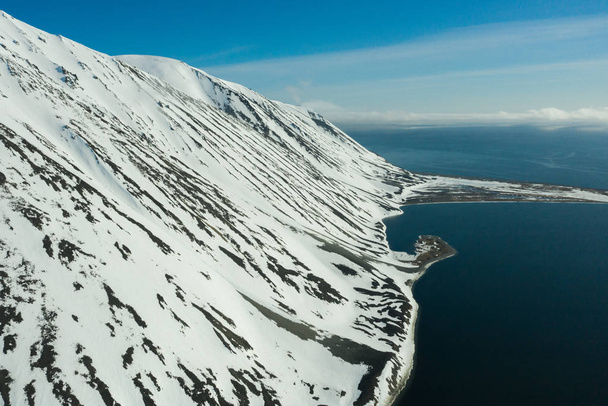 The mountainous sea coast covered with snow in a sunny weather. - Photo, Image