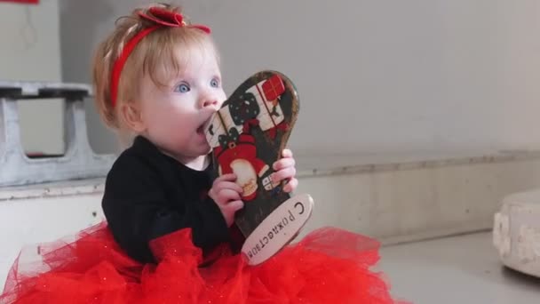 Vánoční koncept - malá holčička hrající si s hračkou se Veselými Vánocemi na to napsala rusky - Záběry, video
