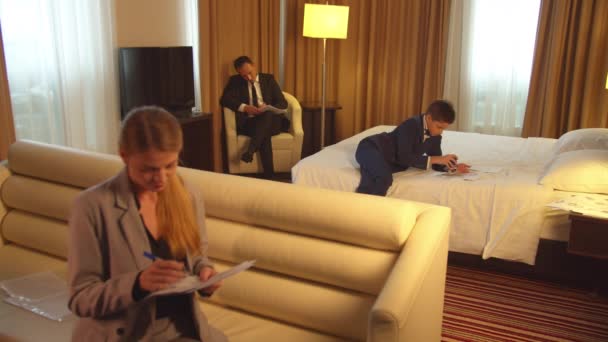 Man, boy and woman in suits work with documents in hotel room - Footage, Video
