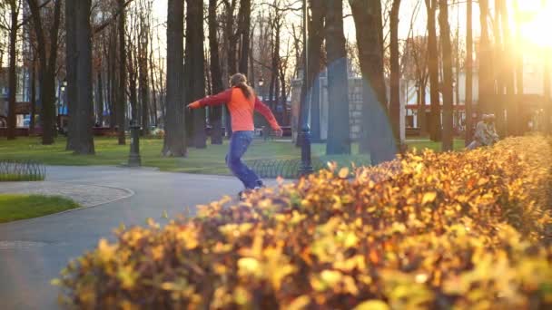 Een professionele mannelijke rolschaatser voert coole trucs en dansen uit op rolschaatsen in een comfortabel stadspark in de laatste dagen van de herfst. Idee van outdoor activiteiten en een gezonde levensstijl in een langzame - Video