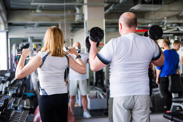 Happy older married couple doing exercises with dumbbells. - Photo, Image