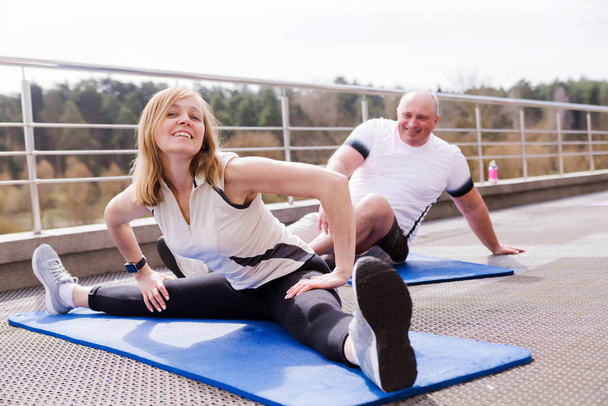 Couple plus âgé s'étirant sur des tapis de gymnastique à l'extérieur
 - Photo, image