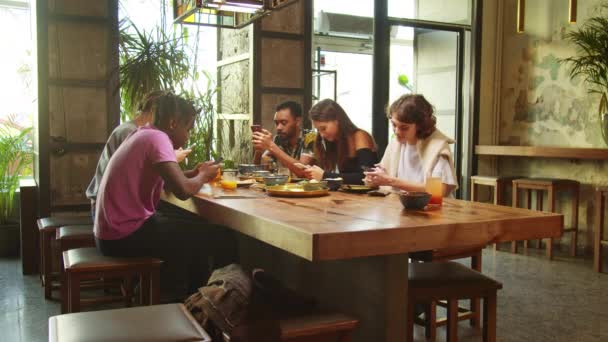 Seitenansicht, Freunde sitzen in einem Café, sie sitzen mit Telefonen in der Hand - Filmmaterial, Video