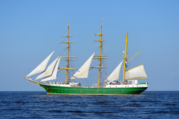 Old historical green tall ship with white sails in blue sea - Photo, Image