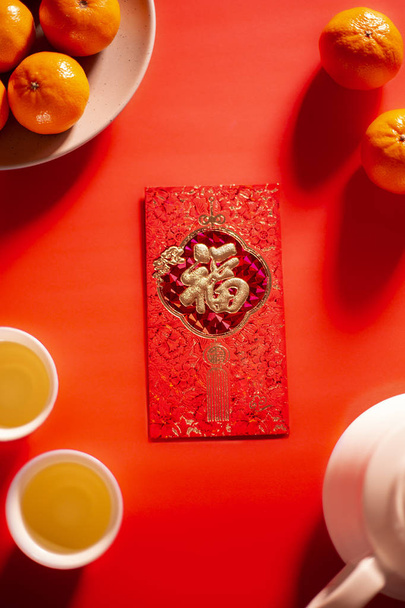 Übersetzungstext auf rotem Umschlag im Bild: Wohlstand und Frühling. Chinesisches Neujahrsfest und Mondneujahr roter Umschlag Orange und heißer Tee. - Foto, Bild