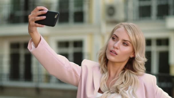 Portret meisje dat selfie maakt op straat. Zakenvrouw fotograferen in roze pak - Video