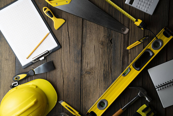 Conceito de empreiteiro. Hardhat amarelo, libella e outras ferramentas sobre o fundo de madeira rústica
. - Foto, Imagem