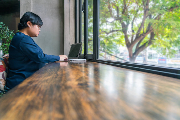 Asian female student using laptop at beautiful garden view coffeeshop - Foto, Imagen
