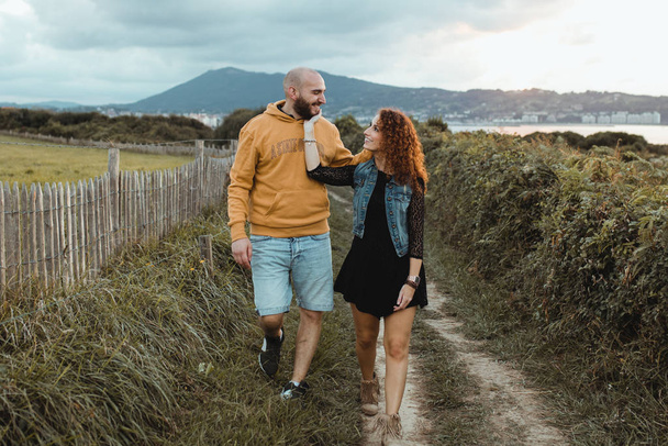 Kochająca czuła kobieta dotykająca podbródka ukochanego mężczyzny spacerując razem po zielonej farmie  - Zdjęcie, obraz