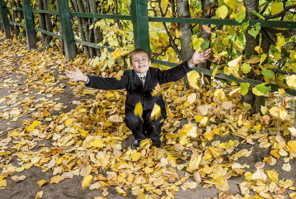 The boy throws the fallen foliage in autumn Park - Foto, Bild