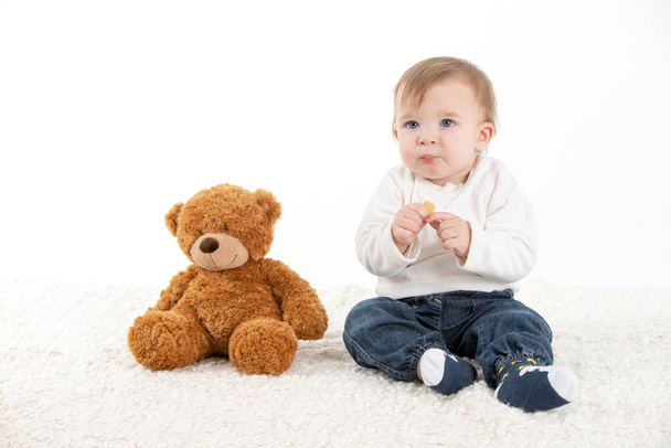 Baby eating with fingers with a teddy bear - Photo, Image