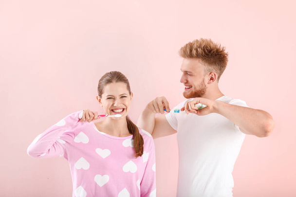 Молодая пара чистит зубы на цветном фоне - Фото, изображение