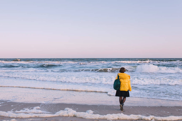 Девушка с рюкзаком стоит одна перед морем
 - Фото, изображение