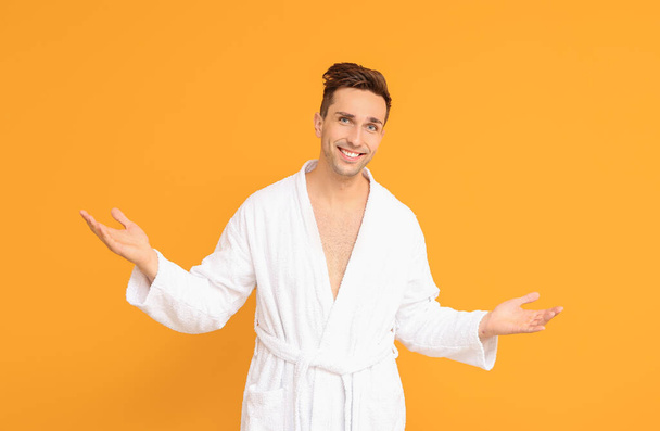 Handsome man in bathrobe on color background - Foto, Imagen