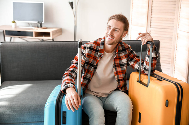 Nuori mies pakattujen matkatavaroiden kanssa kotona
 - Valokuva, kuva