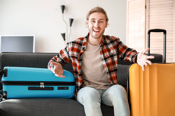 Young man with packed luggage at home - Foto, afbeelding