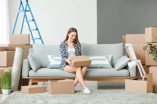 Happy young woman with moving boxes in new house - Fotoğraf, Görsel