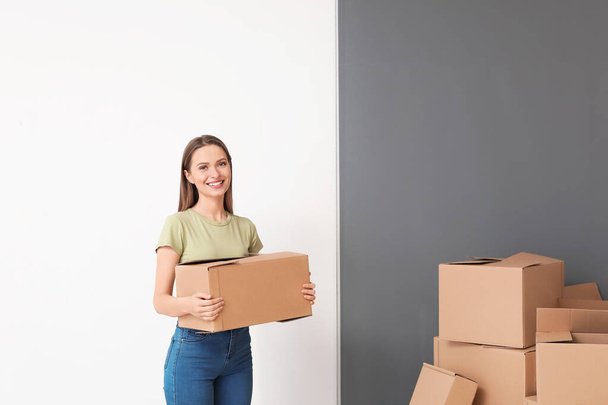 Happy young woman with moving boxes in new house - Photo, image