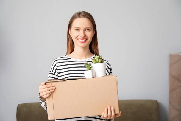 Happy young woman with belongings in new house - Photo, Image