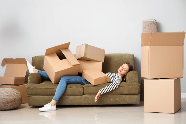 Mulher dormindo com montão de caixas móveis deitado no sofá em casa nova
 - Foto, Imagem