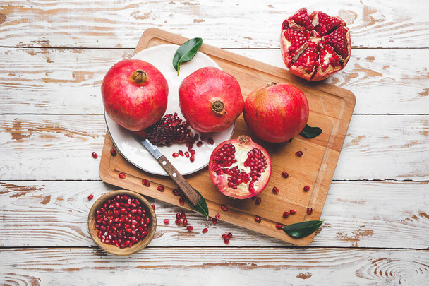 Board with tasty pomegranate on wooden table - Photo, Image