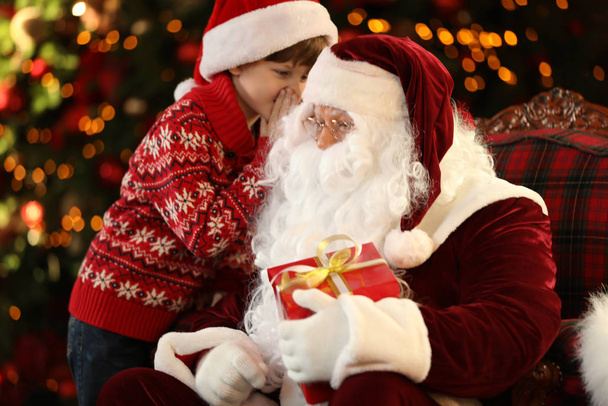 Santa Claus and little boy near Christmas tree indoors - Foto, imagen