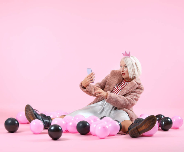 Sorpresa donna matura alla moda con palloncini d'aria e telefono cellulare su sfondo di colore
 - Foto, immagini