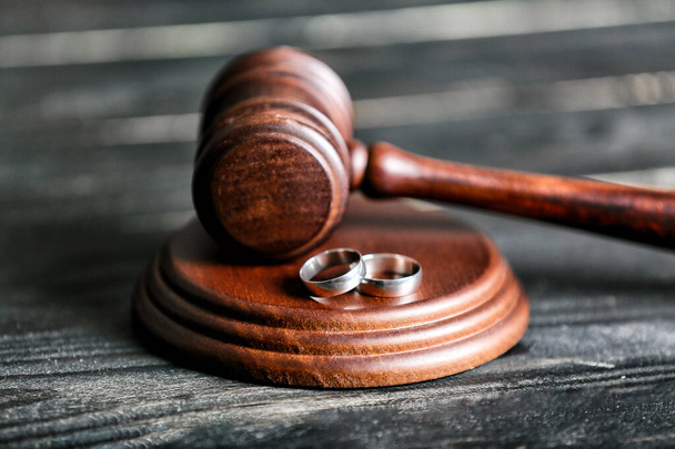 Judge's gavel and rings on wooden background. Concept of divorce - 写真・画像