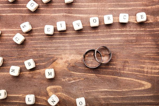 Pair of rings and word DIVORCE made of cubes on wooden background - Photo, Image