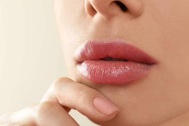 Woman with beautiful full lips on beige background, closeup - 写真・画像