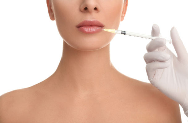 Mujer recibiendo inyección de labios sobre fondo blanco, primer plano
 - Foto, Imagen
