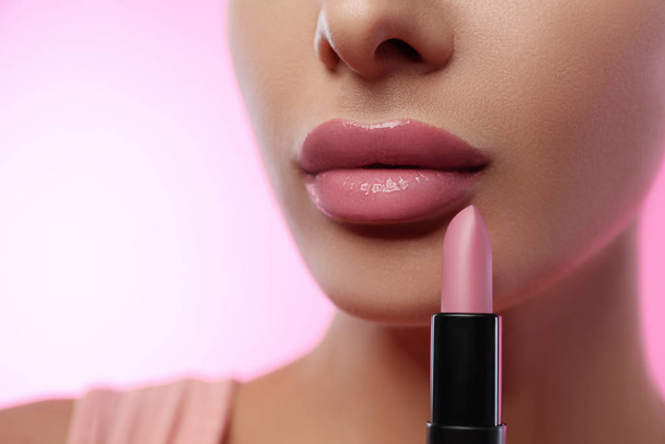 Woman with glossy lipstick on pink background, closeup - Foto, afbeelding