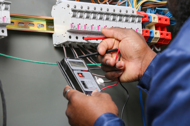 Афроамериканський електрик працює на дистриб'юторській дошці, під'їзді. - Фото, зображення