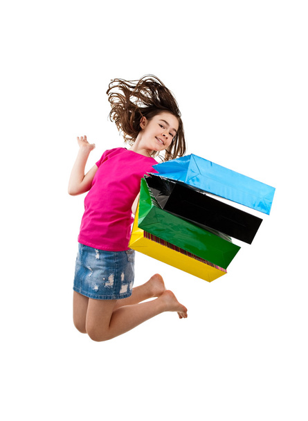 Young girl jumping with shopping bags - 写真・画像
