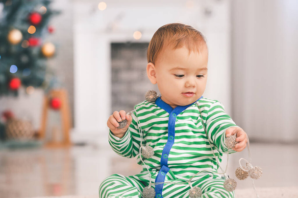 Piccolo bambino carino con ghirlanda in camera decorata per Natale
 - Foto, immagini