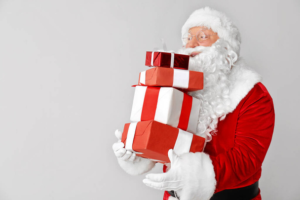 Santa Claus with gifts on light background - Photo, Image