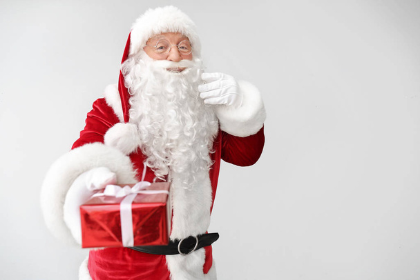 Santa Claus with gift on light background - Foto, Imagen