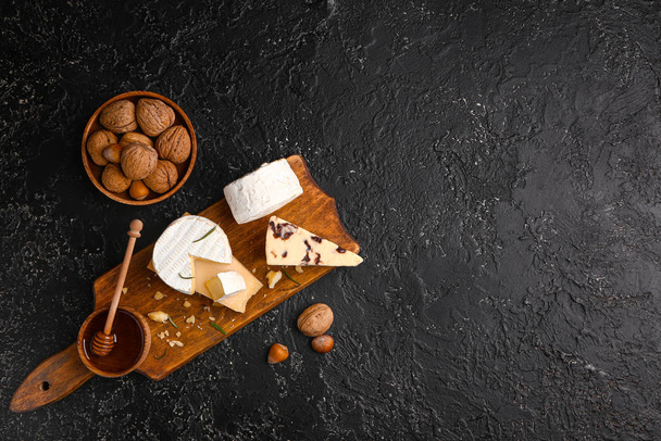 Доска с ассортиментом свежих сыров на темном фоне
 - Фото, изображение